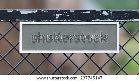 Sign hanging on an old metallic gate - Bring me good news