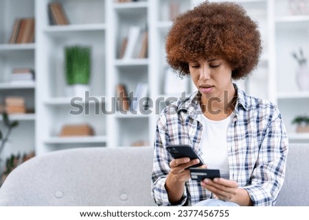 millennial woman holding smartphone and banking credit card, involved in online mobile shopping at home