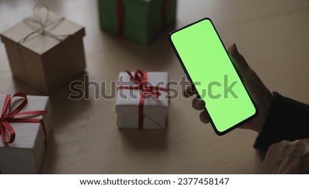 old female hands holding smartphone with green screen and celebrating holiday chatting with family