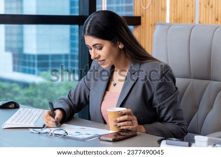 Businesswoman analyzing annual business report at office desk