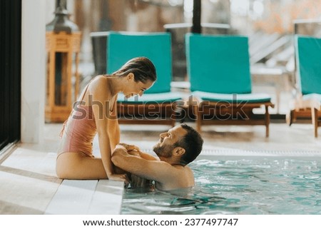 Handsome young couple relaxing in the indoor swimming pool Royalty-Free Stock Photo #2377497747