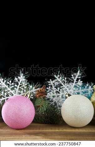 branch of fir-tree, snowflakes and new-year decorations on a black background