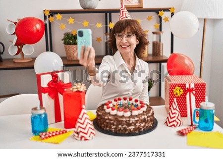 Middle age woman celebrating birthday make selfie by smartphone at home
