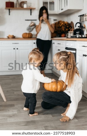 family prepares pumpkins for Halloween. Photo on a light background of a happy family surrounded by pumpkins. Parents help children