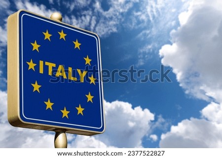 Closeup of a modern Italian border road sign with the European Union flag, against a blue sky with clouds and copy space. 