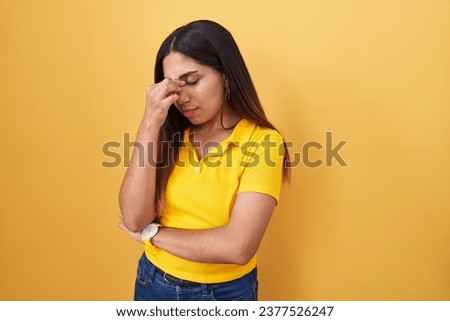 Young arab woman standing over yellow background tired rubbing nose and eyes feeling fatigue and headache. stress and frustration concept. 