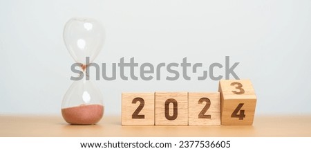 flipping block 2023 to 2024 text with hourglass on table. Resolution, time, plan, goal, motivation, reboot, countdown  and New Year holiday concepts Royalty-Free Stock Photo #2377536605