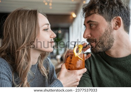 Handsome man and young woman smiling on happy hour at cocktail bar - Young lovers couple at beginning of love story - Boyfriend and girlfriend hanging out together enjoying after work fancy drinks Royalty-Free Stock Photo #2377537033
