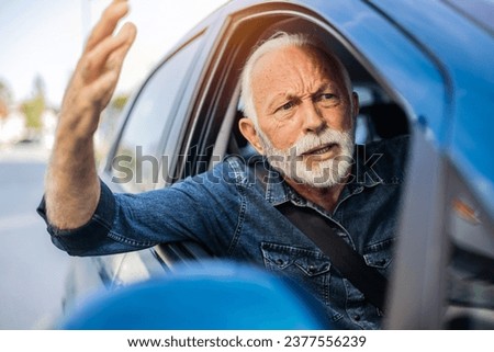 Angry senior man yelling out car window. Frustrated mature man driving a car and shouting at other driver.