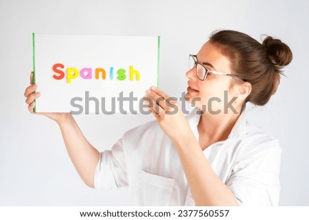 Learning Spanish educational courses. Native tutor, woman teacher in glasses with magnetic sign in hands. Study foreign language in online school. Speaking,reading,writing,linguistic knowledge skills.