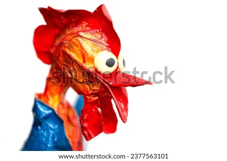 The muzzle of a funny fairy-tale rooster made of papier mache on a white background.
