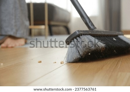 Home cleaning. Close up of woman doing housework, holding a broom and sweeping floor Royalty-Free Stock Photo #2377563761