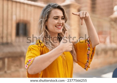 Young woman smiling confident doing photo gesture with hands at street