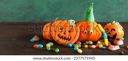 Paper pumpkins for Halloween and tasty sweets on wooden table. Banner for design