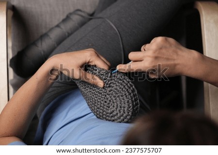 Woman knitting on sofa at home, closeup. Cozy atmosphere
