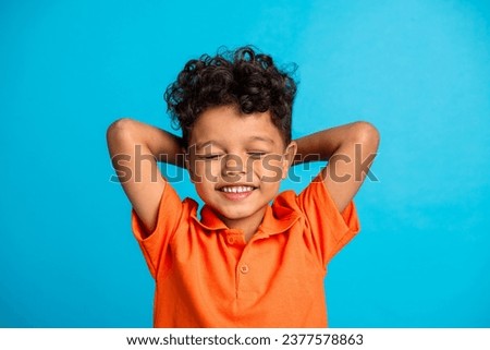 Photo of calm child boy sleeping relax hands over head isolated on blue color background