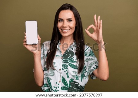 Photo of cheerful stunning lady wear trendy print clothes demonstrates empty space modern device isolated on beige color background
