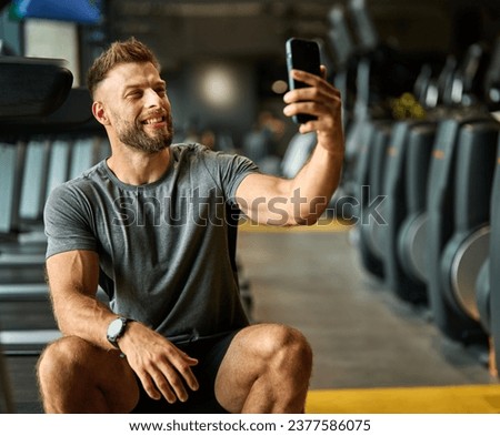 Portrait of a young man using a phone ana making a selfie photo, taking a break exercising in a gym, running using  thereadmill machine equipment, healthy lifestyle and cardio exercise at fitness 