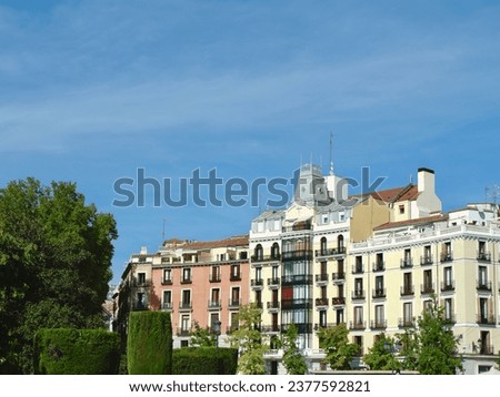 Classical elegant buildings seen though vivid park greenery on Plaza del Oriente, Madrid, Spain. Vintage Spanish architecture.