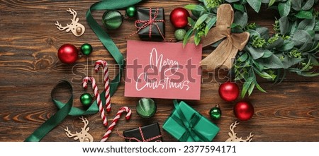 Greeting card with text MERRY CHRISTMAS, gift boxes and decor on wooden background