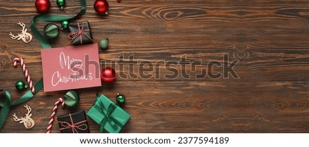 Greeting card with text MERRY CHRISTMAS, gift boxes and decor on wooden background with space for text