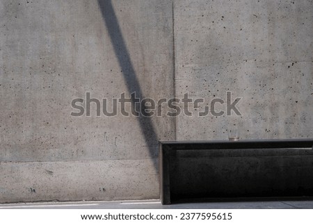 Concrete in the sun with shadow falling on the bench with glass of water 