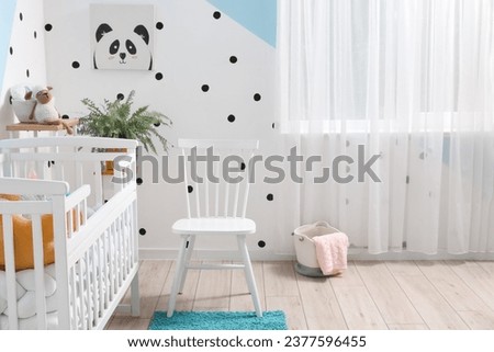 Interior of stylish children's bedroom with crib, chair and picture