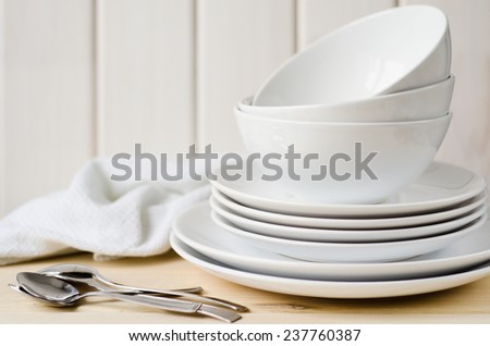 white large and small plates and bowls on a light table Royalty-Free Stock Photo #237760387