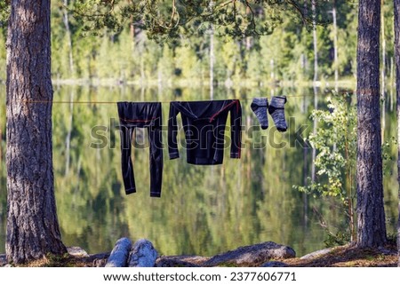 Tourist thermal underwear are dried on the shore of a forest lake in the morning. The background is blurred. Royalty-Free Stock Photo #2377606771