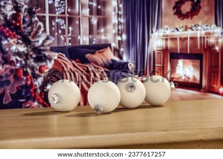 Glasses christmas balls on desk and blurred home interior background. 