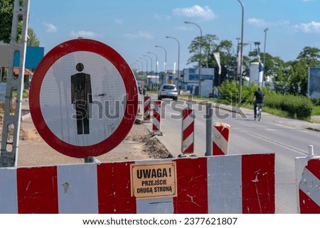 Renovation of the street. Sign"no pedestrian traffic!" and inscription "ATTENTION! CROSS THE OTHER SIDE".Dug up road in the city under blue sky. A barrier blocking the passage through dug-up sidewalks