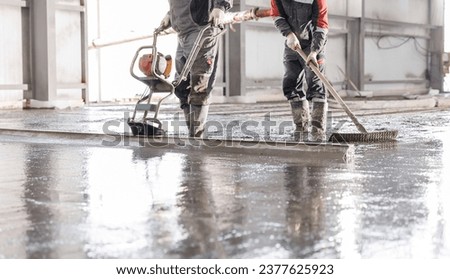 Workers uses vibrating machine to level cement mortar for floors. Concrete screed for buildings, construction site. Royalty-Free Stock Photo #2377625923