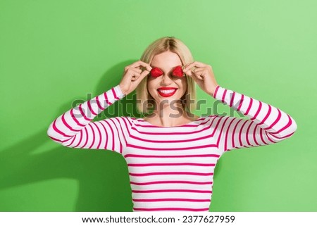 Photo of joking childish nice young girl playing cover her face eyes sweet strawberries temptation isolated on green color background