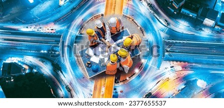 Top view of engineers team, male and female put hands on top over blueprint, solar photovoltaic equipment, road and wind turbine business important infrastructure on solar panel at construction site. Royalty-Free Stock Photo #2377655537