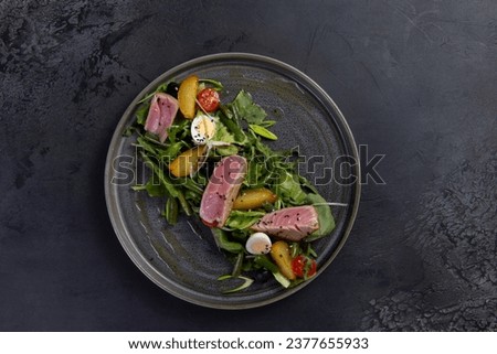 Salad with pieces of fried tuna on a dark background. Selective focus.