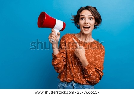 Photo portrait of lovely young lady point loudspeaker excited dressed stylish brown garment isolated on blue color background