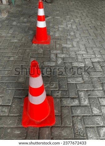 Two red traffic cones mixed with white, placed on the paving road