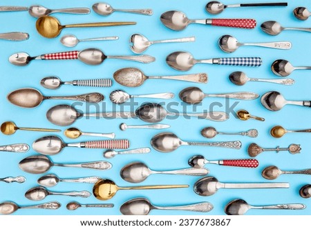 Cutlery. Top view photo of variety of antique silverware and gold kitchen spoons arranged against blue studio background. Concept of food, holiday, table setting, retro, vintage. copy space