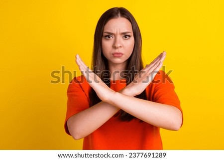 Lady making stop gesture with her palm, on yellow background.