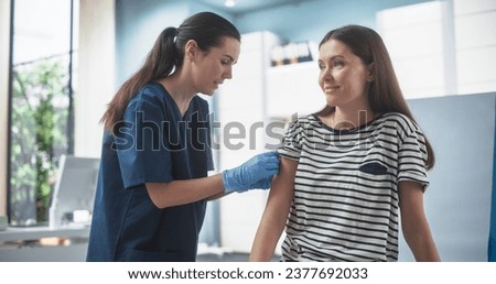 Happy Caucasian Woman Sitting In The Chair In Bright Hospital And Getting Her Chicken Pox Vaccine. Professional Female Nurse Is Performing Injection And Putting A Patch On. Public Healthcare Concept. Royalty-Free Stock Photo #2377692033