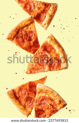 Flying food. Pizza pepperoni slices with cheese, sausages, salami and spices in levitation on yellow background. Vertical orientation Royalty-Free Stock Photo #2377693815