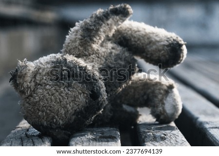 Conceptual image: Russia's war against Ukraine, ruined children's lives as a result of Russian aggression, loss childhood and future. Teddy bear lying down outdoors. Broken toys, broken life Royalty-Free Stock Photo #2377694139