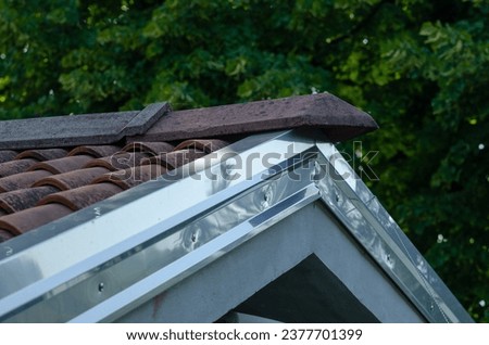 roof of a house: cornice with galvanized steel sheet, detail of the house on the part of the double-sided roof with ridge tiles. roof flashing,