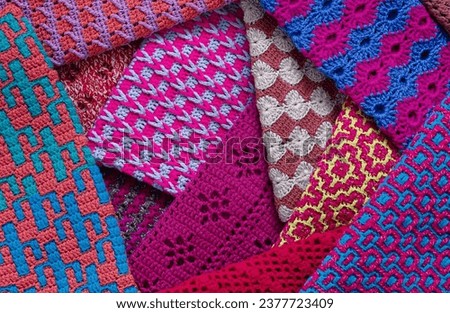 Many colorful crochet fabrics with different patterns. Knitted background.