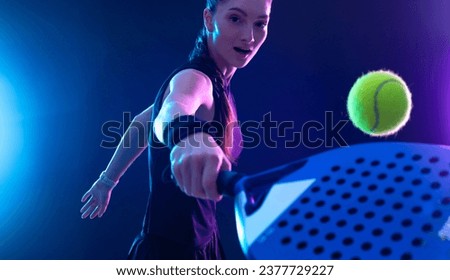 Padel tennis player with racket on tournament. Girl athlete with paddle racket on court with neon colors. Sport concept. Download a high quality photo for design of a sports app or tour events. Royalty-Free Stock Photo #2377729227
