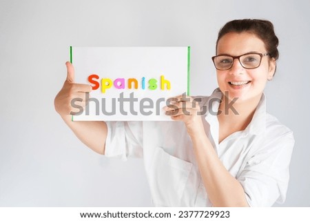 Learning Spanish educational courses. Native tutor, woman teacher in glasses with magnetic sign in hands. Study foreign language in online school. Speaking,reading,writing,linguistic knowledge skills.