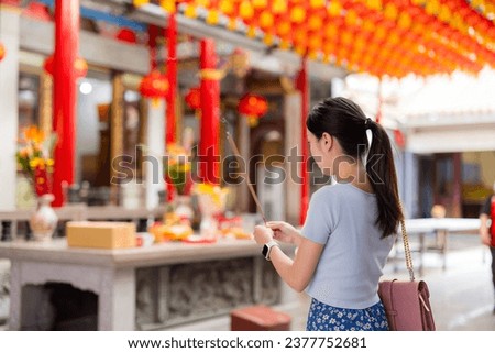 Woman holding smoking incense sticks in chinese temple Royalty-Free Stock Photo #2377752681