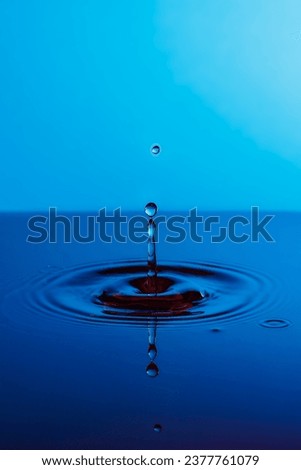 Closeup of water drop hitting water and creating a splash and a nice reflection in still water