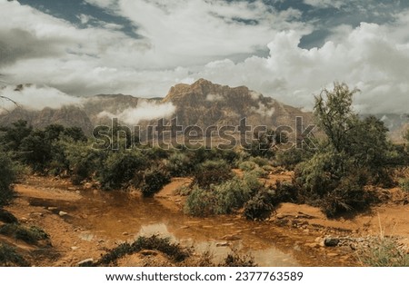 Landscape of Redrock National Park in the State of Nevada, United States. You can see the desert valley and the enormous red rock mountains, as well as the storm clouds in the sky.