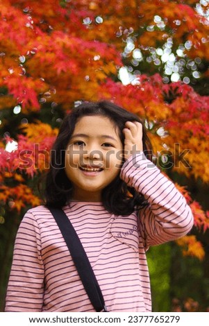 Little girl photographed in a red acer palmatum park in autumn